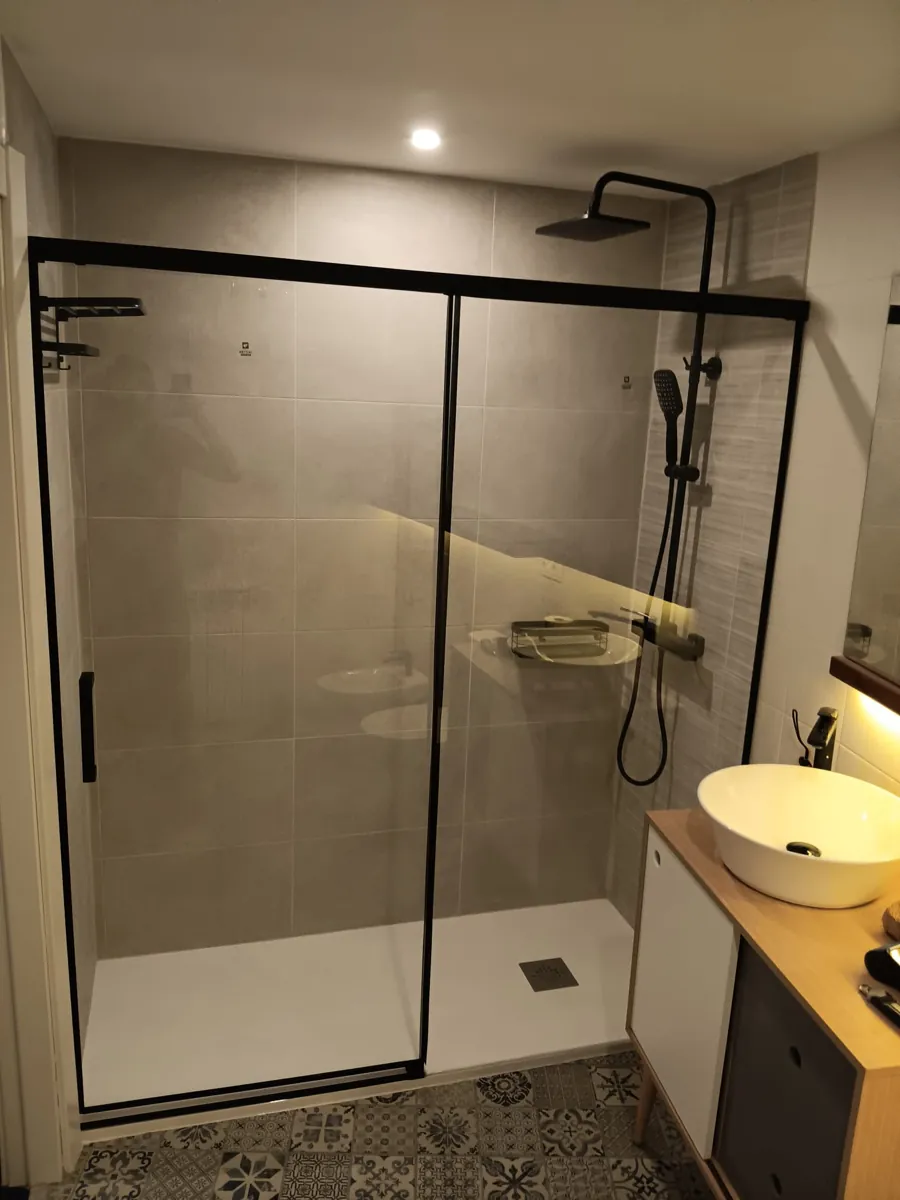 Ducha con mampara de perfil negro y lavabo redondo